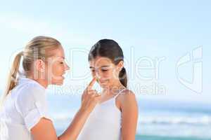 Mother applying sun cream on her daugter's nose