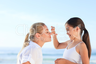 Little girl applying sun cream on her mother's face