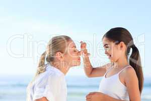 Little girl applying sun cream on her mother's face