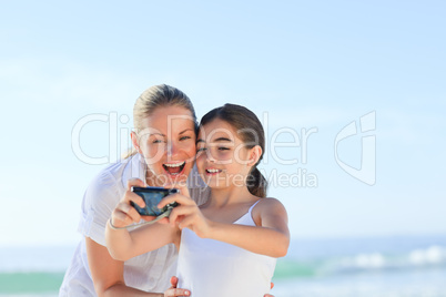 Little girl taking a photo of herself and her mother