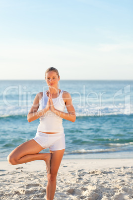 Woman practicing yoga on the beach