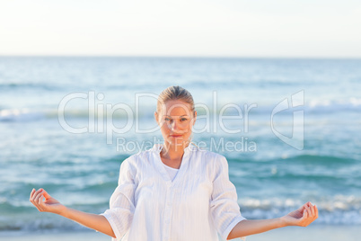 Active woman practicing yoga on the beach