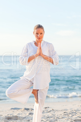 Active woman practicing yoga on the beach