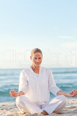 Active woman practicing yoga on the beach