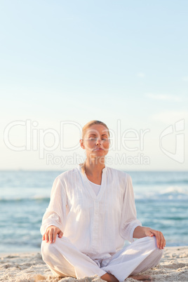 Active woman practicing yoga on the beach