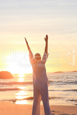 Woman practicing yoga during the sunset at the beach