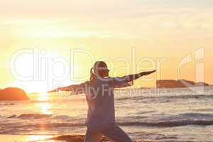 Woman practicing yoga during the sunset at the beach