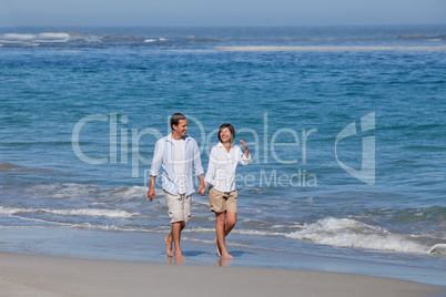 Couple walking on the beach under the sun