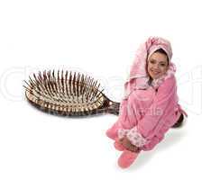 Girl in a pink dressing gown sits on a hairbrush