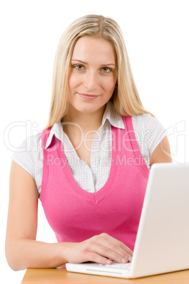 Happy teenager woman sitting at table with laptop