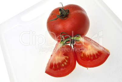 Cutting white plastic board with red tomato