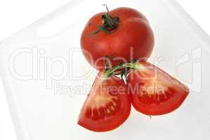 Cutting white plastic board with red tomato