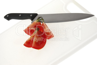 Cutting white plastic board with a knife and tomato