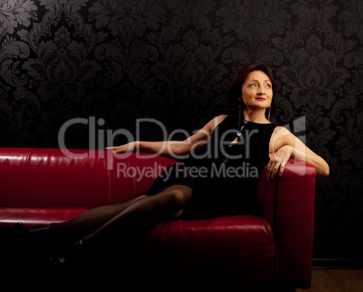 Beauty mature woman sit on red sofa