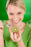 Healthy lifestyle - happy woman holding kiwi on green