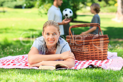 Father and son playing football while the mother is reading