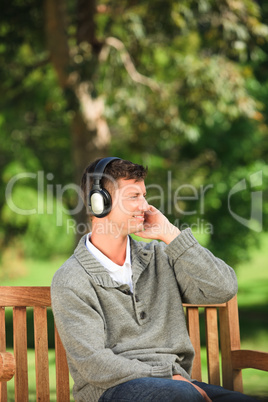 Young man listening to some music on the bench