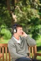 Young man listening to some music on the bench