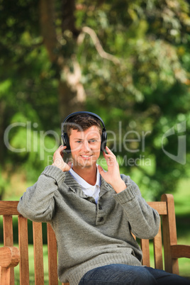 Young man listening to some music on the bench