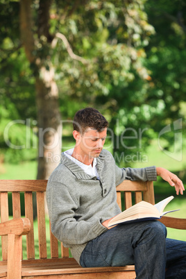Young man reading his book on the bench