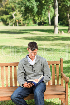 Young man reading his book on the bench