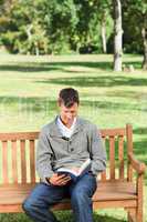 Young man reading his book on the bench