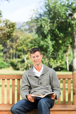 Young man reading his book on the bench Young man reading his book on the bench