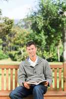 Young man reading his book on the bench