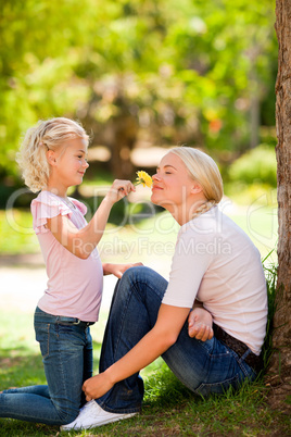 Mother and her daughter smelling a flower