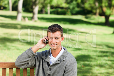 Young man phoning on the bench