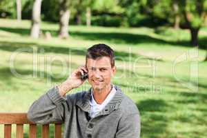 Young man phoning on the bench