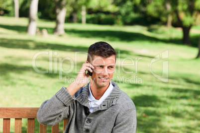 Young man phoning on the bench