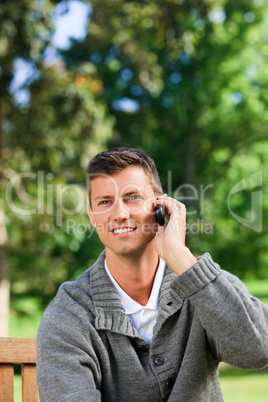 Young man phoning on the bench