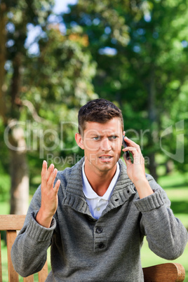 Young man phoning on the bench