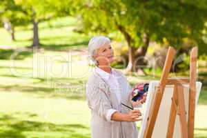 Senior woman painting in the park