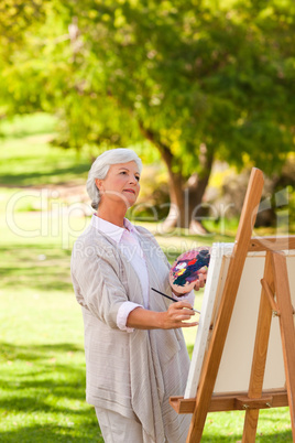 Senior woman painting in the park