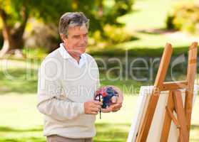 Elderly man painting in the park