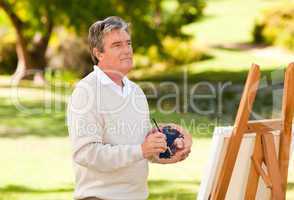 Elderly man painting in the park
