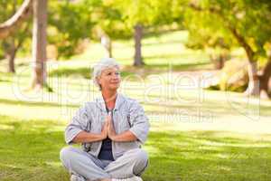 Mature woman practicing yoga in the park