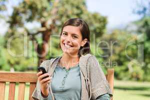 Young woman phoning on the bench