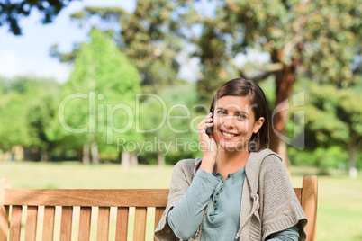 Young woman phoning on the bench