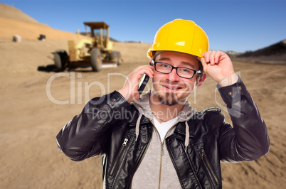 Young Cunstruction Worker on Cell Phone in Dirt Field with Tract