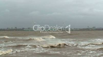 Stormy sea with wind turbines in background