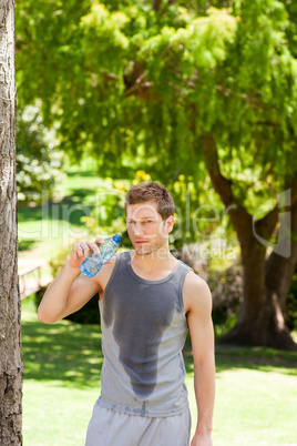 Sporty man drinking water in the park