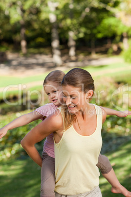 Beautiful mother giving daughter a piggyback