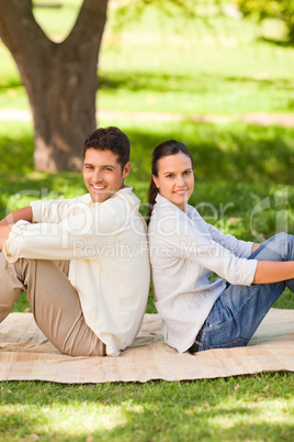 Couple sitting back to back in the park