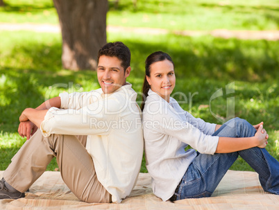 Couple sitting back to back in the park