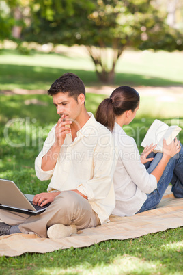 Man working on his laptop while his wife is reading