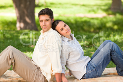 Lovers sitting back to back in the park