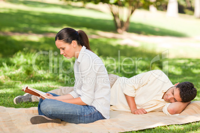 Woman reading while her husband is sleeping